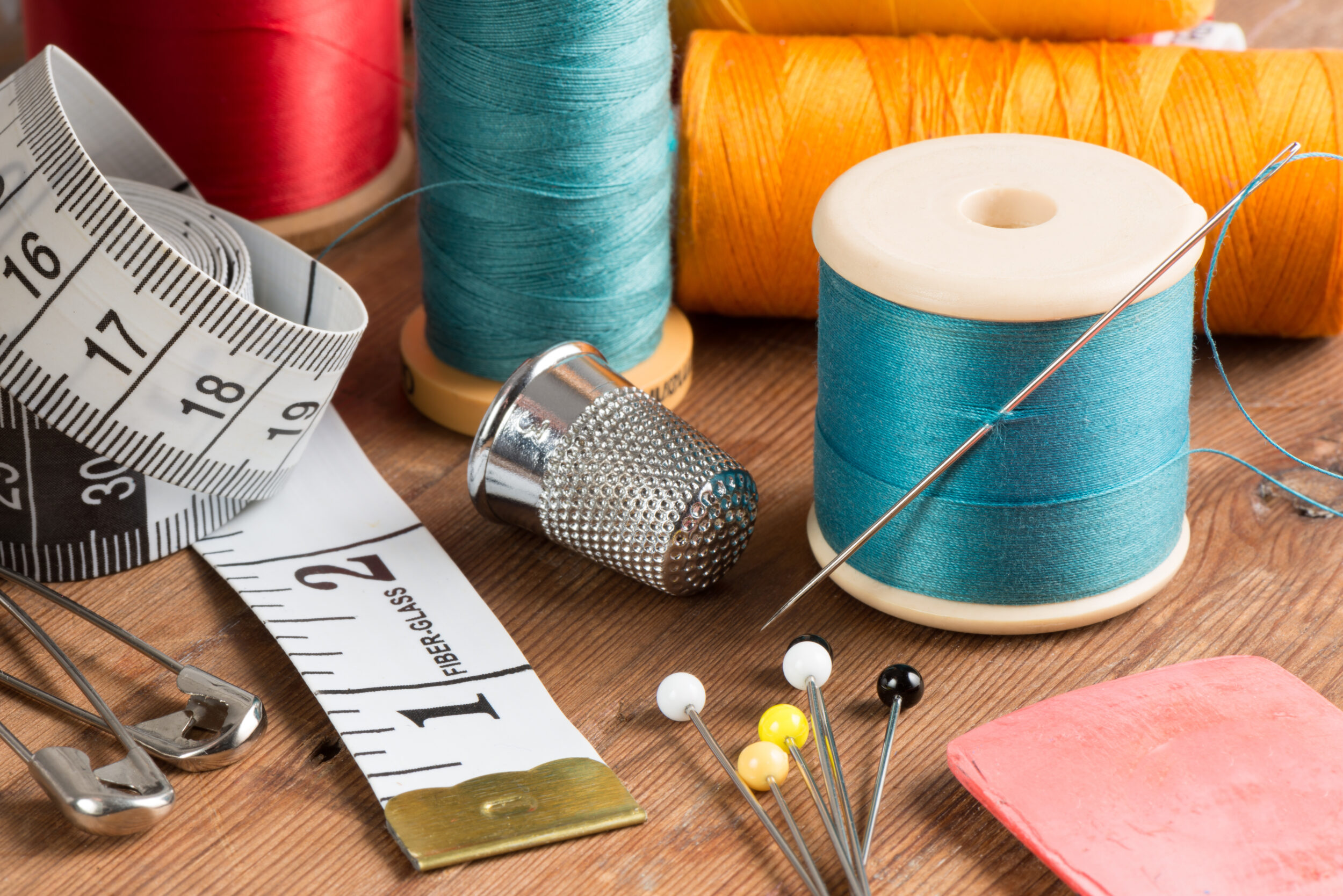 Spools of thread and basic sewing tools including pins and needles.